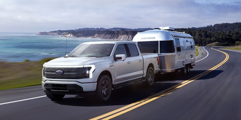 White Ford F-150 Lightning towing an Airstream trailer